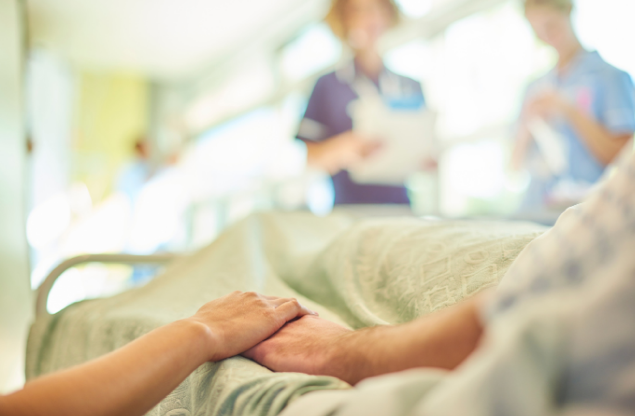 person on hospital bed holding hands with a loved one