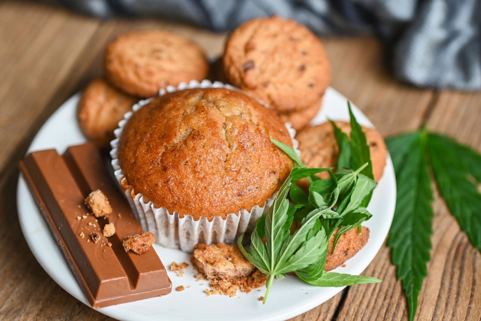 a plate of muffin, cookies, chocolate and a marijuana leaf